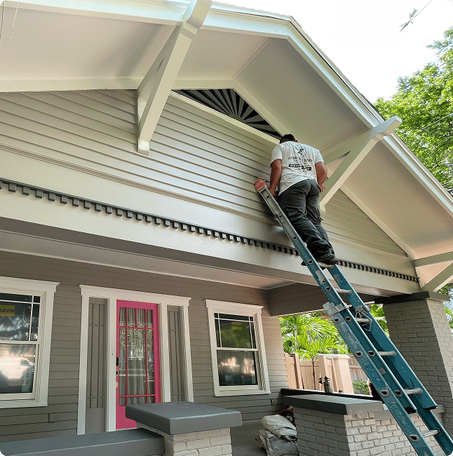 Professional painter on ladder painting house exterior